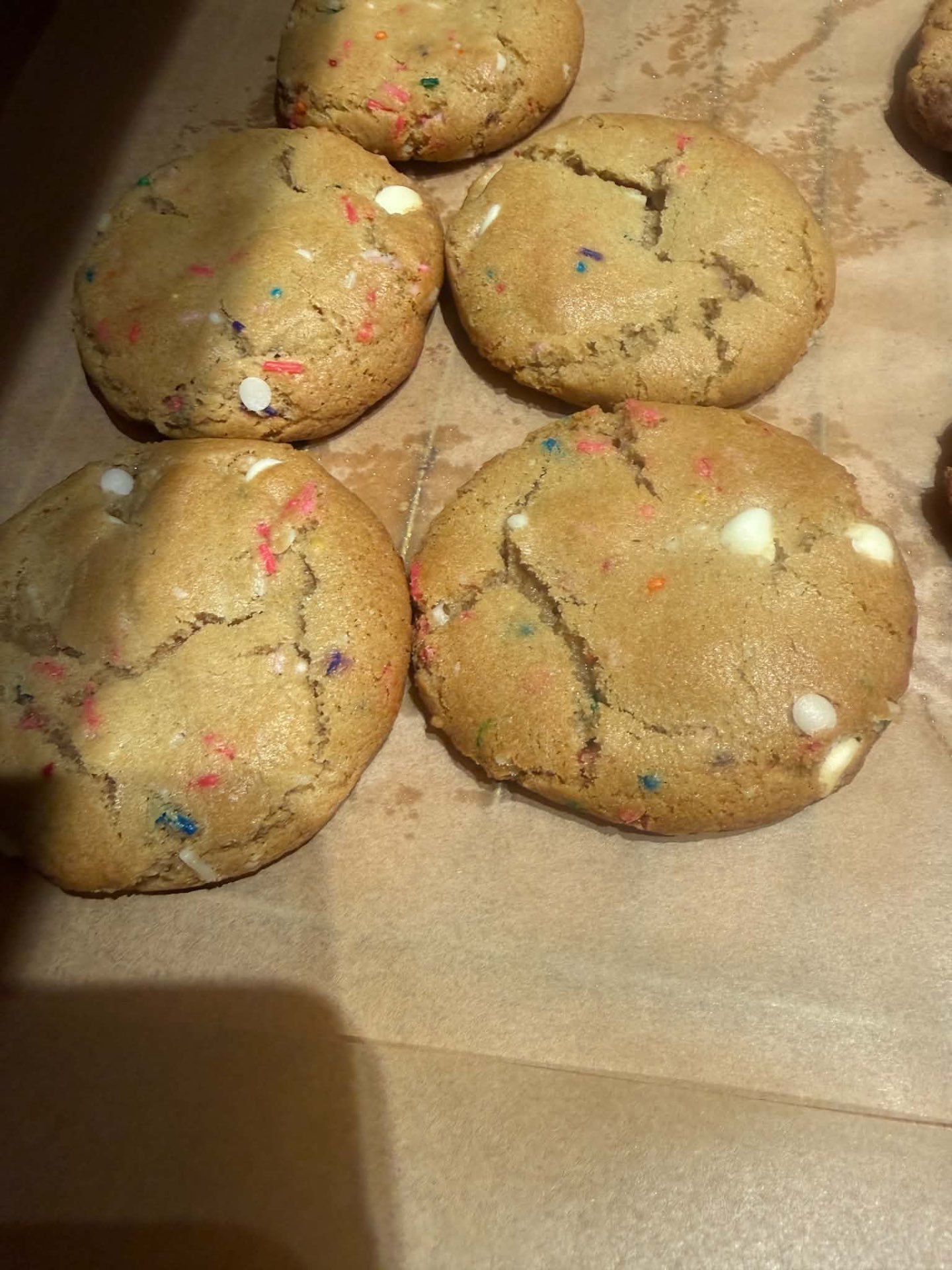 Golden cookies with colorful sprinkles and white baking chips on a tray
