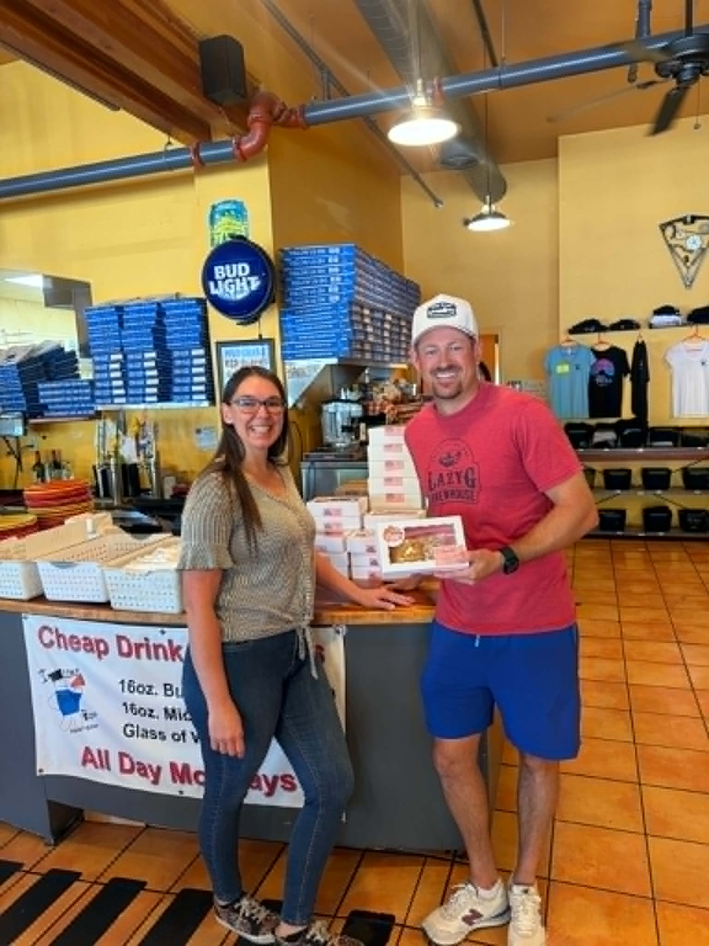 Tiffany Alford and the owner of Bill's Pizza holding a box of Mommy & Me Goodies cookies
