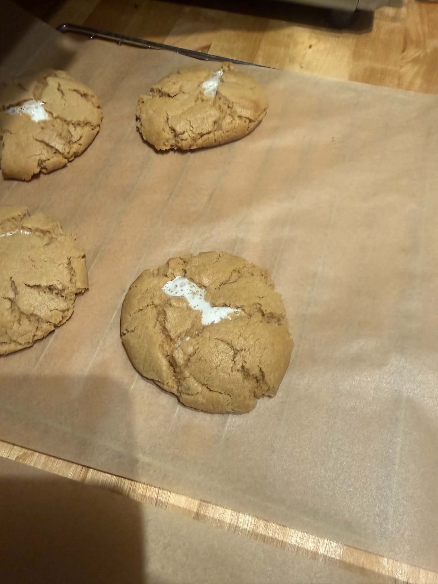 Golden homemade cookies with a soft white center on parchment paper